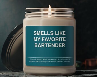 May include: A scented candle in a glass jar with a silver lid. The label says "SMELLS LIKE MY FAVORITE BARTENDER" in white text on a teal background. The candle is on a reflective surface.