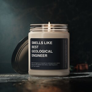 Pode incluir: Uma vela perfumada num frasco de vidro com tampa prateada. O rótulo diz "SMELLS LIKE BEST GEOLOGICAL ENGINEER". A vela está numa superfície escura com a tampa parcialmente aberta. O texto abaixo diz "Allow the fragrance of growth to embrace your career, filling you with passion and drive, inspiring you to reach new heights."