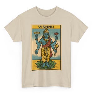 Puede incluir: Camiseta beige con un gráfico de Vishnu, una deidad hindú. La ilustración representa a Vishnu con piel azul, sosteniendo una flor de loto y un disco. La palabra "VISHNU" está impresa en amarillo en la parte superior del gráfico.