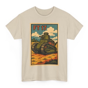 May include: Beige t-shirt with a retro illustration of an FT 17 tank. The design includes the text "FT 17" in red, set against a backdrop of fields and sky. The tank is rendered in shades of green and brown.