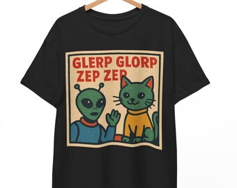 Może przedstawiać: Czarny t-shirt z kreskówkowym kosmitą i zielonym kotem w żółtej koszulce. Grafika zawiera tekst "GLERP GLORP ZEP ZER" w czerwonych literach na beżowym tle. Kosmita macha.