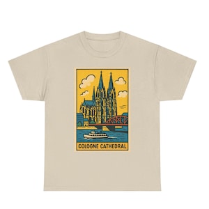 Puede incluir: Camiseta beige con un diseño rectangular de la Catedral de Colonia. El diseño incluye la catedral, un puente, un barco y el texto "COLOGNE CATHEDRAL" en amarillo y azul. Tema de viaje.