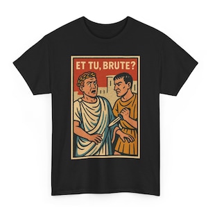 Puede incluir: Camiseta negra con una ilustración retro de dos figuras romanas. Una figura sostiene un cuchillo, y el texto "ET TU, BRUTE?" se muestra en un recuadro rojo. El diseño tiene un estilo de cómic vintage.