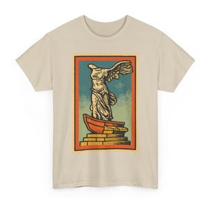 Puede incluir: Camiseta beige con un diseño gráfico de estilo vintage de la estatua de la Victoria de Samotracia. La obra de arte está enmarcada en naranja y rojo, con un fondo azul y verde. La estatua está representada en tonos crema y beige.
