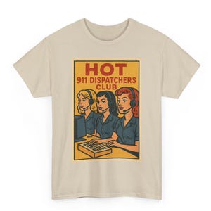 Puede incluir: Camiseta beige con un gráfico retro de tres mujeres con auriculares, con el texto "HOT 911 DISPATCHERS CLUB" en un diseño amarillo y rojo. Las mujeres visten camisas azules.