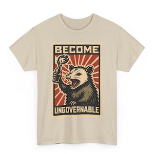 May include: Beige t-shirt featuring a graphic of an opossum holding a Molotov cocktail with the words "BECOME UNGOVERNABLE" in a red and black design.