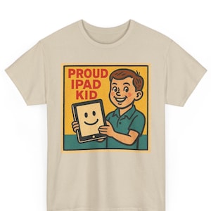 May include: Beige t-shirt featuring a retro-style graphic. The graphic shows a smiling boy holding a tablet with a smiley face. The text "PROUD IPAD KID" is above the boy and tablet.