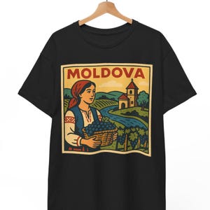Könnte beinhalten: Schwarzes T-Shirt mit einer Illustration im Vintage-Stil. Das Wort "MOLDOVA" steht oben. Die Grafik zeigt eine Frau in traditioneller Kleidung, die einen Korb mit Trauben hält, mit einer Kirche und Landschaft im Hintergrund.