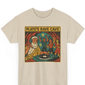 May include: Beige t-shirt featuring a colorful graphic. The graphic depicts Plato with headphones, a turntable, and dancing figures, with the text "PLATO'S RAVE CAVE" above. The design is in a retro cartoon style.