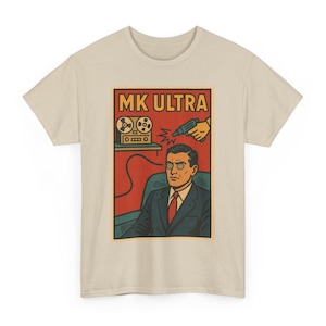 May include: Beige t-shirt featuring a retro-style graphic with the text "MK ULTRA." The graphic depicts a man in a suit with hypnotized eyes, a tape recorder, and a hand holding a ray gun. The design is in shades of red, orange, and blue.