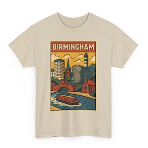May include: A beige t-shirt with a graphic print of Birmingham, England. The design shows a river scene with a boat, buildings, and the word "BIRMINGHAM" in a rectangular frame. The shirt is made of a soft material.