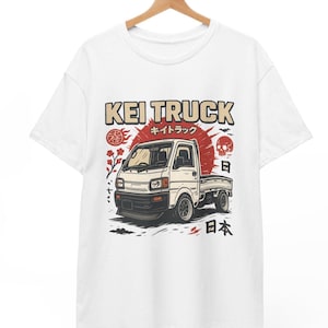 Peut inclure: T-shirt blanc avec un imprimé graphique d'un camion kei blanc avec un soleil rouge et du texte japonais qui dit "KEI TRUCK" et "キイトラック".