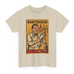 Pode incluir: Camiseta bege com um gráfico em estilo vintage de um barman. O gráfico mostra um barman sorrindo agitando um coquetel, com garrafas e um copo de martini. A palavra "BARTENDER" é impressa na parte superior do gráfico.