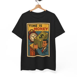 May include: Black t-shirt featuring a vintage-style graphic. The graphic includes the text "TIME IS MONEY" above an image of an alarm clock, a stack of money, and a man in a suit.
