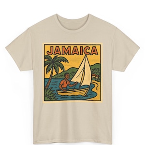 May include: Beige t-shirt featuring a rectangular graphic with the word "JAMAICA" in yellow. The graphic depicts a sailboat on the water, a palm tree, and a person in a boat. The design has a vintage, travel-themed aesthetic.