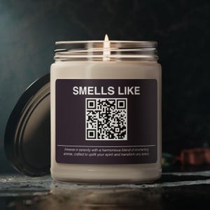 Peut inclure: Un bocal de bougie beige avec une étiquette noire sur laquelle est inscrit "SMELLS LIKE" et un code QR noir et blanc. L'étiquette comprend également le texte "Immerse in serenity with a harmonious blend of enchanting aromas, crafted to uplift your spirit and transform any space."