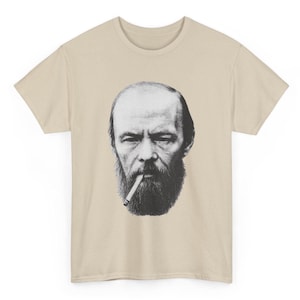 Może przedstawiać: Beżowa koszulka z czarno-białym portretem brodatego mężczyzny z papierosem. Grafika znajduje się na środku przodu koszulki. Koszulka ma krótkie rękawy i okrągły dekolt.