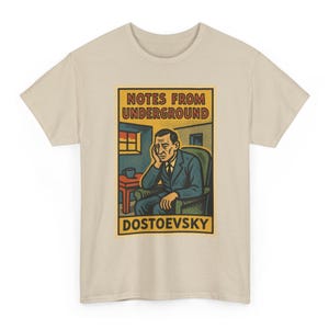 May include: Beige t-shirt featuring a vintage-style graphic from "Notes from Underground" by Dostoevsky. The design includes an illustration of a man in a chair, a window, and the author's name. The shirt is made of a soft material.