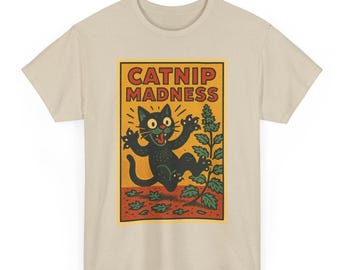 Może przedstawiać: Beżowa koszulka z grafiką z napisem "CATNIP MADNESS". Grafika przedstawia czarnego kota z zielonymi oczami, otoczonego liśćmi kocimiętki. Projekt jest w stylu vintage, kreskówkowym.