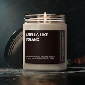 May include: A white candle in a glass jar with a black label that reads "SMELLS LIKE POLAND". The label also includes the text "Allow the tender fragrance of Poland to embrace your senses, filling you with warmth and comfort."