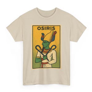 Puede incluir: Camiseta beige con un gráfico de Osiris, una antigua deidad egipcia. La ilustración representa a Osiris con piel verde, un tocado amarillo y sosteniendo un báculo y un flagelo. La palabra "OSIRIS" está impresa encima de la figura en letras doradas.