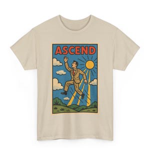 May include: Beige t-shirt featuring a retro-style graphic. The graphic depicts a man in a suit reaching towards a bright sun, with the word "ASCEND" in a red banner above. The design includes clouds, rays of light, and a green landscape.