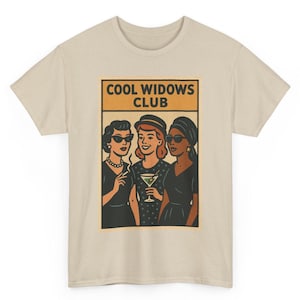 Peut inclure: T-shirt beige avec une illustration rétro de trois femmes en robes noires et lunettes de soleil, avec le texte "COOL WIDOWS CLUB" dans un rectangle orange. Une femme tient une cigarette, une autre un martini.