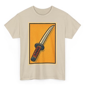 May include: Beige t-shirt featuring a rectangular graphic of a traditional Japanese sword. The sword has a silver blade, a black and red handle, and a blue hilt, set against an orange background.