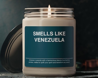 May include: A white candle in a glass jar with a teal label that reads "SMELLS LIKE VENEZUELA". The label also includes the text "Immerse in serenity with a harmonious blend of enchanting aromas, crafted to uplift your spirit and transform any space."