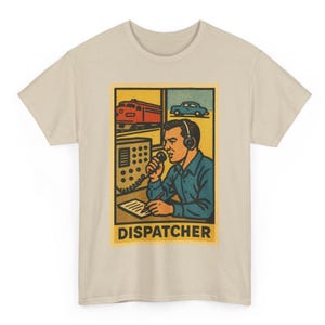 May include: Beige t-shirt featuring a retro-style graphic of a dispatcher. The graphic shows a man with a headset, a microphone, and a control panel, with a train and car in the background. The word "DISPATCHER" is printed below the image.