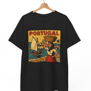May include: Black t-shirt with a vintage-style illustration of a woman carrying a basket of fruit and a sailboat in front of a cityscape. The illustration is surrounded by a yellow border with the word "PORTUGAL" in red letters.