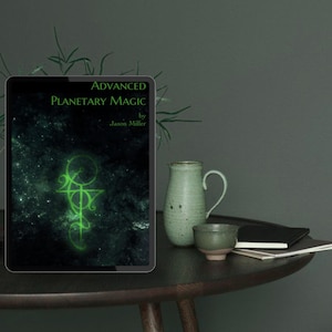 Puede incluir: Una tableta muestra la portada de "Advanced Planetary Magic" de Jason Miller. El texto y un símbolo verde brillante destacan sobre un fondo oscuro y estrellado. Una jarra y una taza verdes se encuentran sobre una mesa de madera oscura.