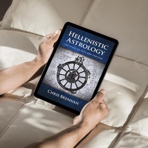May include: A tablet displaying the cover of "Hellenistic Astrology: The Study of Fate and Fortune" by Chris Brennan. The cover features a dark blue banner with white text and a circular design with Greek text. The tablet is held by two hands.
