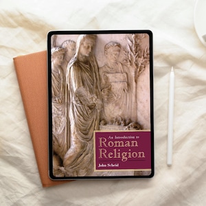 Puede incluir: Una tableta digital que muestra la portada de un libro titulado "An Introduction to Roman Religion" de John Scheid. La portada presenta una escultura en relieve de figuras. Un cuaderno naranja quemado y un lápiz óptico blanco están junto a la tableta.
