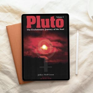 Può includere: Un tablet che mostra la copertina del libro "Pluto: The Evolutionary Journey of the Soul, Volume I" di Jeffrey Wolf Green. La copertina presenta uno sfondo rosso e nero con un'immagine luminosa gialla simile al sole. Uno stilo bianco e un taccuino marrone sono accanto al tablet.