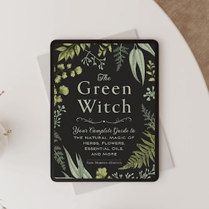 Könnte beinhalten: Ein Buch mit dem Titel The Green Witch: Your Complete Guide to the Natural Magic of Herbs, Flowers, Essential Oils, and More von Arin Murphy-Hiscock. Der schwarze Einband zeigt einen dekorativen Rand aus grünen Pflanzenmotiven.