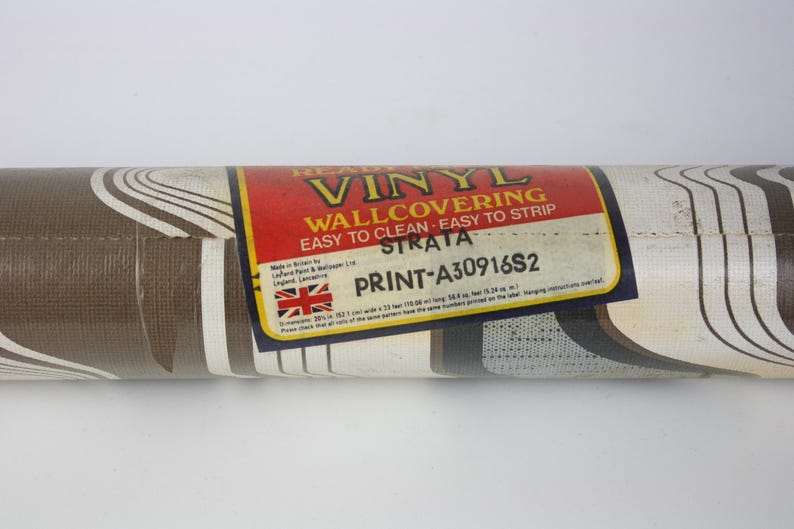 Op de afbeelding: Een rol bruin en wit vinyl behang met een golvend patroon. Het label vermeldt "Heavy Vinyl Wallcovering Easy to Clean - Easy to Strip Strata Print-A30916S2"