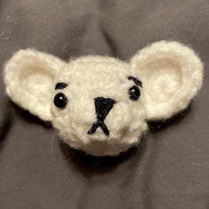 May include: A white crocheted stuffed animal with black eyes and a black nose. The animal has large ears and a small mouth.