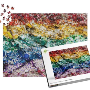 Può includere: Un puzzle colorato con un design arcobaleno, con sfumature di rosso, arancione, giallo, verde, blu e viola. Il puzzle è parzialmente assemblato, con alcuni pezzi sparsi nelle vicinanze. La scatola mostra il puzzle completo e recita "Rainbow in the Atlantic Ocean NORMA HYBRID".