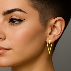 Op de afbeelding: Goudkleurige geometrische oorbellen. Elke oorbel heeft een kleine driehoekige stud die is verbonden met een grotere omgekeerde driehoek. De oorbellen hebben een heldere, effen gouden kleur en worden op het oor gedragen.