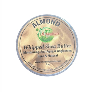 May include: A gold and white container of Almond Whipped Shea Butter by Mine Botanicals. The label reads "Moisturizing, Anti-Aging & Brightening, Pure & Natural, www.minebotanicals.com, 8 oz., Especially Beneficial for Dry & Dehydrated Skin."