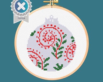 May include: A white Christmas bauble with a red and green floral design. The bauble is in a wooden embroidery hoop.