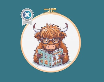 Op de afbeelding: Een kruissteekpatroon van een Schotse hooglander die een bril draagt en een boek leest. De koe is bruin en wit met een pluche manen. Het boek is open en heeft kleurrijke illustraties.