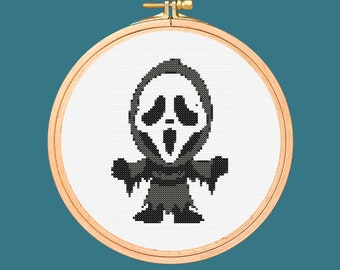 May include: A white embroidery hoop with a black and white cross-stitch design of a ghost wearing a mask. The ghost has a wide, open mouth and a scream face.