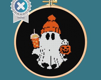 May include: A white ghost wearing an orange knit hat and holding a pumpkin and a cup of coffee. The ghost is on a black background.