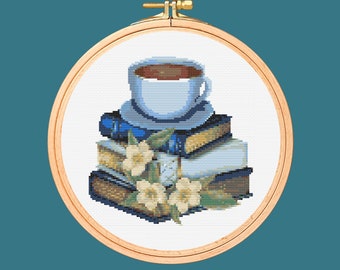 May include: A cross-stitch embroidery design featuring a white coffee cup with brown coffee on a stack of books with white flowers.