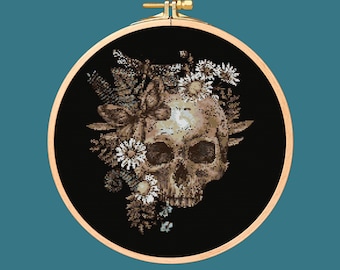 May include: A black and white cross-stitch embroidery hoop featuring a detailed skull with a floral wreath of white flowers and leaves.