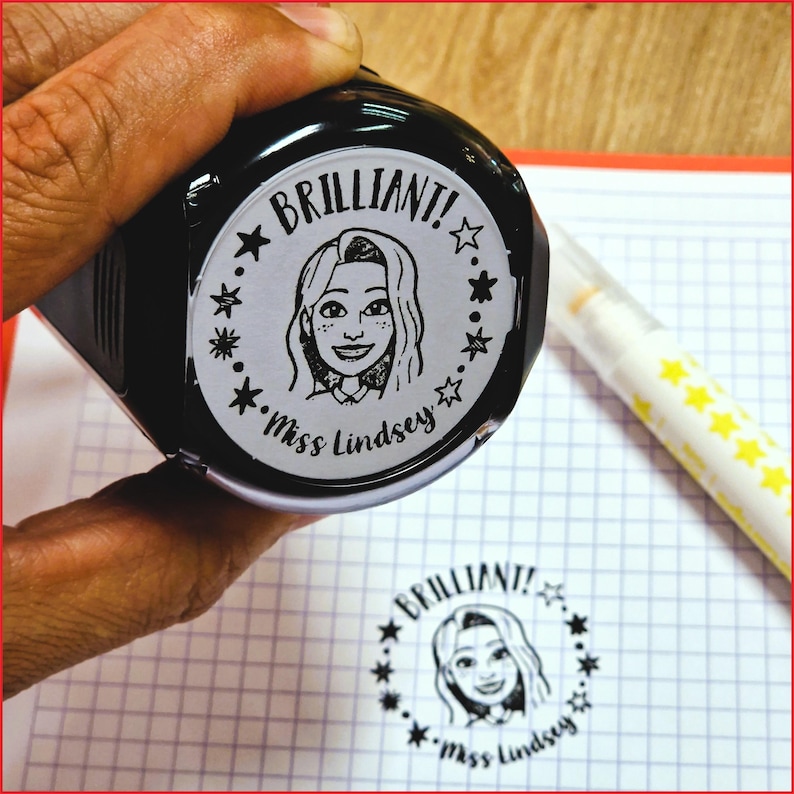 K&ouml;nnte beinhalten: Ein schwarzer Stempel mit dem Wort "BRILLIANT!" und dem Namen "Miss Lindsey", der eine Cartoon-Illustration einer Frau umkreist. Der Stempel wird &uuml;ber einem karierten Papier mit einem gestempelten Abdruck des gleichen Designs und einem gelben Textmarker gehalten.