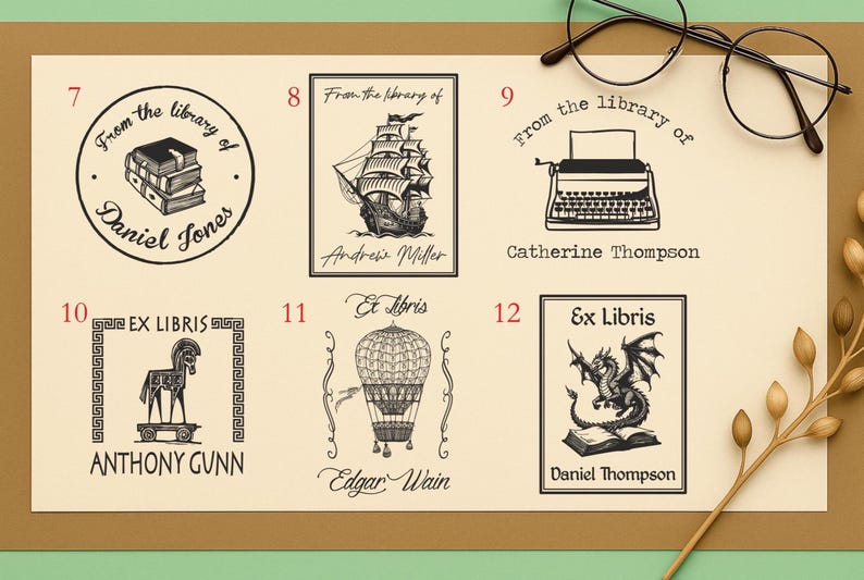 May include: A collection of six black and white book stamps with various designs. The stamps include a stack of books, a sailboat, a typewriter, a horse, a hot air balloon, and a dragon. Each stamp includes a name.