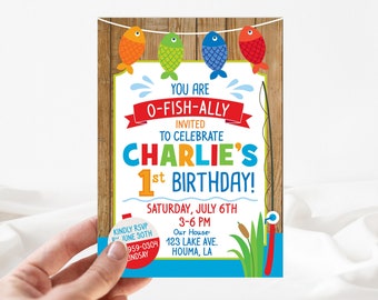 May include: A colorful invitation for a 1st birthday party with a fishing theme. The invitation features a wooden background with a fishing rod, fish, and the text "You are O-Fish-Ally Invited to Celebrate Charlie's 1st Birthday!"  The invitation also includes the date, time, and location of the party.